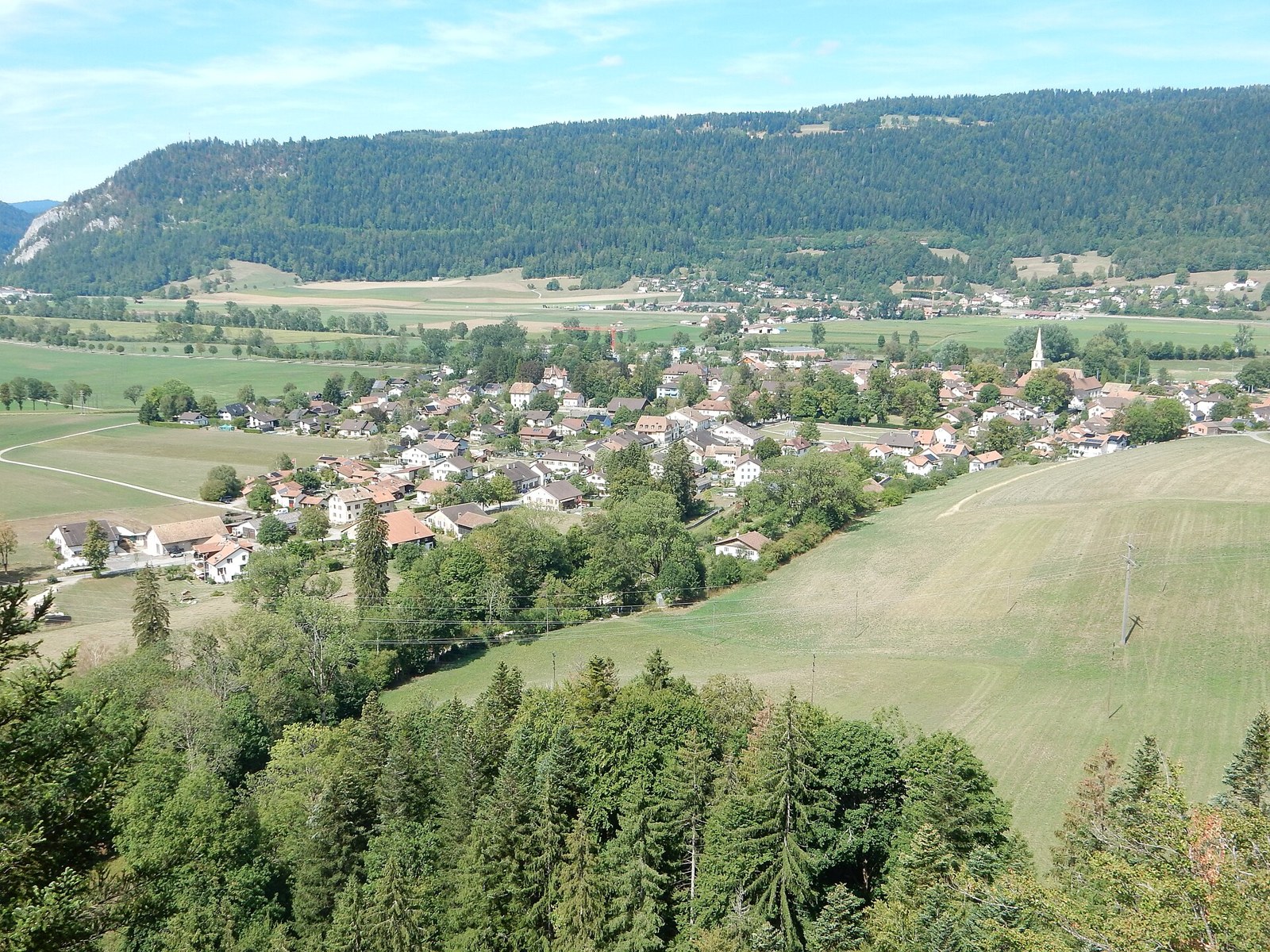 The village of Môtiers in the Val-de-Travers seen from the south in summer